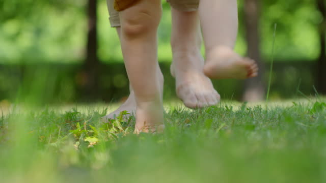 Beine-der-Frau-und-Kind-zu-Fuß-auf-dem-Rasen-barfuß