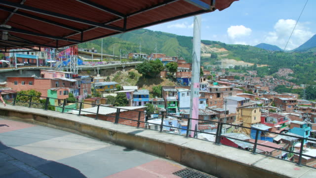 Niña-camina-en-pasarela-bajo-techo-con-vista-del-barrio-de-la-Comuna-13,-Medellín-Colombia