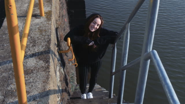 Junge-lächelnde-Frau-stehend-auf-Fluss-Treppe