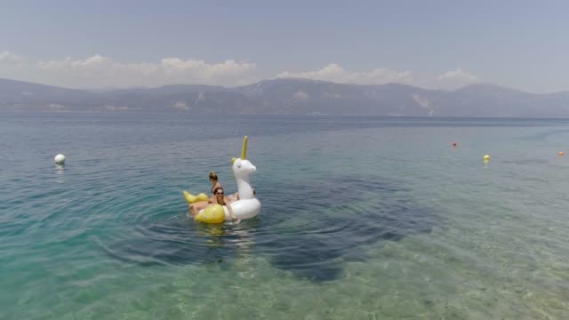 Vista-aérea-de-dos-mujeres-flotando-en-inflable-en-Panagopoula,-Grecia.