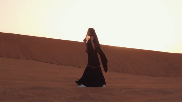 Muslimische-Frau-steht-in-der-Nähe-von-Moschee-in-der-Wüste.-Starker-Wind-Nahostfrieden-ohne-Krieg