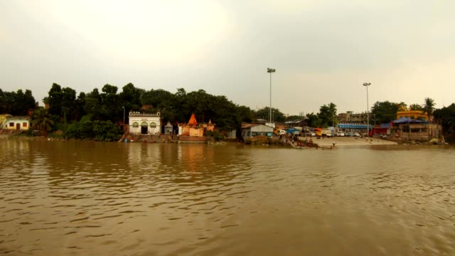 ghat-indische-Treppe-zum-Fluss-Hoogli-Menschen-waschen-Kleidung-waschen-sich-grüne-Bäume-und-Palmen-auf-Bankblick-von-schwimmenden-Boot-Kolkata-bewölkten-Tag