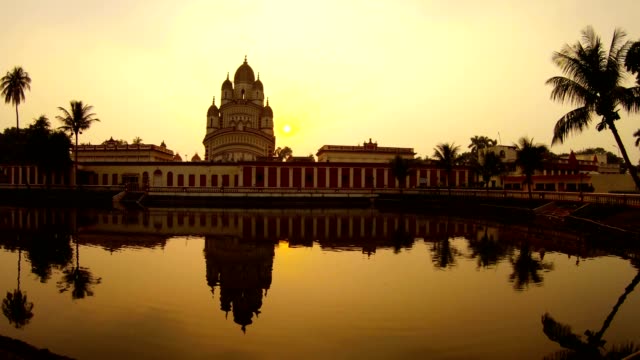 Ramakrishna-misión-sol-se-cae-cerca-de-la-reflexión-del-templo-Kali-en-estanque-coloridos-palmeras-de-la-puesta-de-sol-Kolkata