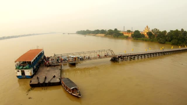 Muelle-cargando-pasajeros-a-bordo-del-ferry-Kali-Mata-Temple-en-la-orilla-del-río-Hooghly-vista-superior-Ramakrishna-misión-Kolkata-puesta-de-sol