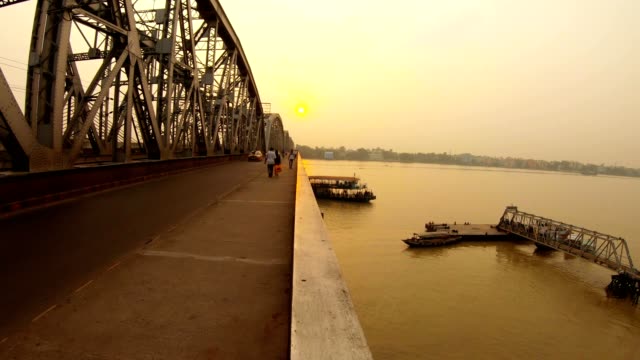 Ferry-boat-swims-up-to-pier-under-Nivedita-bridge-cars-pedestrians-on-road-near-Ramakrishna-mission-sunset