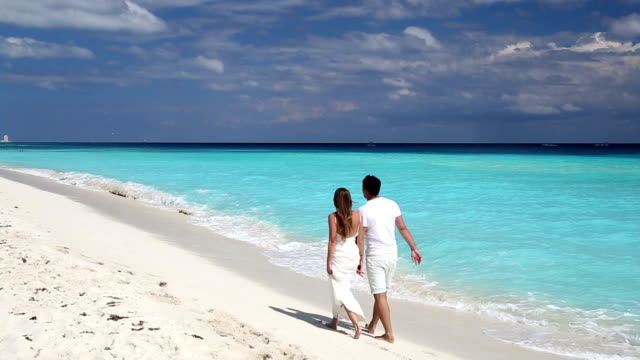 Junge-schöne-Paar-in-Liebe-Hände-halten,-zu-Fuß-am-tropischen-Strand