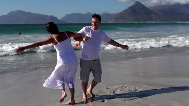 Slow-motion-of-romantic-couple-spinning-around-on-the-beach,-Cape-Town,South-Africa