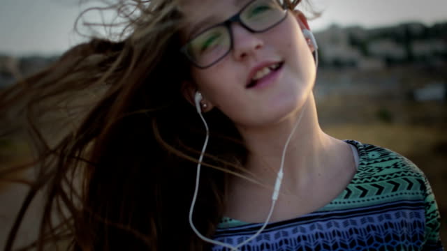 Teenager-Mädchen-mit-eyeglasses-hören-Sie-die-Musik-und-Gesang-im-Freien