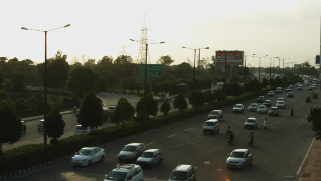 Locked-on-shot-of-traffic-moving-on-city-street,-Delhi,-India
