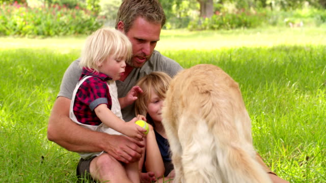 Dad-plays-with-his-cute-sons-and-their-dog-outside