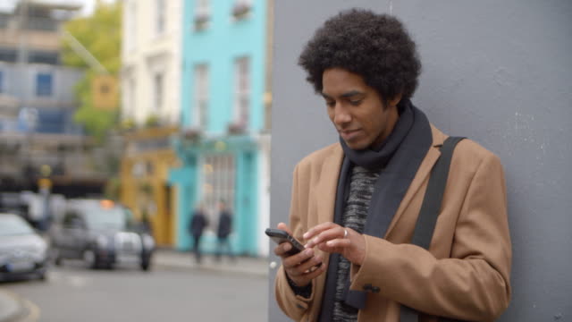 Young-Man-Using-Phone-On-Busy-City-Street