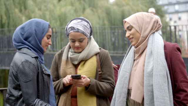 Muslimischen-Freundinnen-mit-Handy-im-städtischen-Umfeld