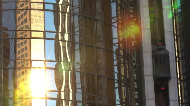 Moderne-Bürogebäude-Glasaufzug-in-Sonnenstrahlen-nach-unten-bewegen
