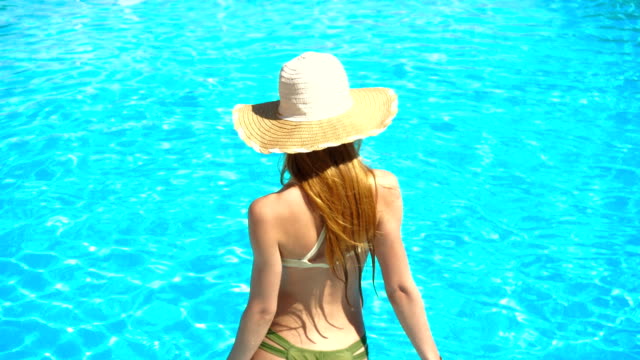 Junge-Mädchen-in-sexy-Badeanzug-und-Hut-geht-in-das-Wasser-im-pool