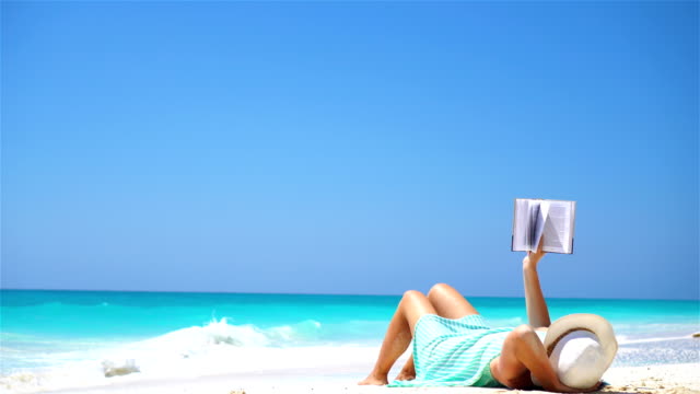 Young-woman-reading-book-during-tropical-white-beach