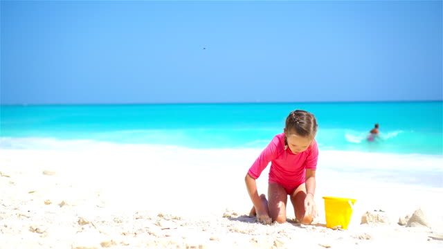 Entzückende-kleine-Mädchen-spielen-mit-Spielzeug-für-den-Strand-am-weißen-Sandstrand
