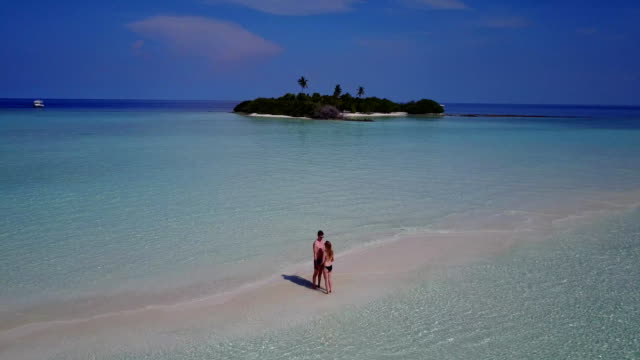 v03900-Aerial-flying-drone-view-of-Maldives-white-sandy-beach-2-people-young-couple-man-woman-romantic-love-on-sunny-tropical-paradise-island-with-aqua-blue-sky-sea-water-ocean-4k