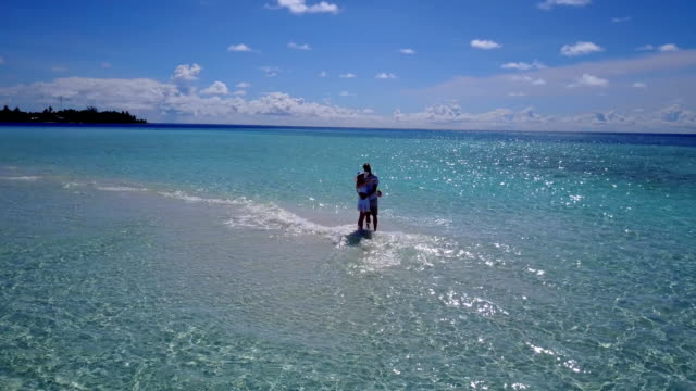 v03930-fliegenden-Drohne-Luftaufnahme-der-Malediven-weißen-Sandstrand-2-Personen-junges-Paar-Mann-Frau-romantische-Liebe-auf-sonnigen-tropischen-Inselparadies-mit-Aqua-blau-Himmel-Meer-Wasser-Ozean-4k