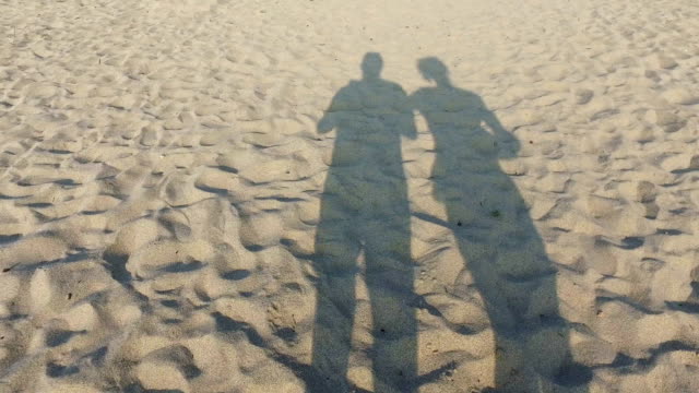 Frisch-verliebte-Paare,-die-am-Strand-mit-romantischen-Schatten-auf-dem-sand