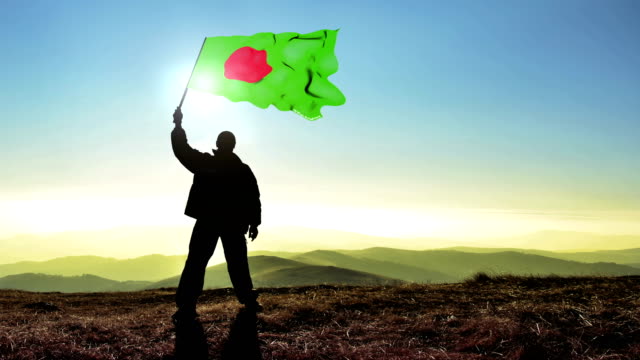 Ganador-de-exitosa-silueta-hombre-ondeando-la-bandera-de-Bangladesh-en-la-parte-superior-del-pico-de-la-montaña.-Fondo-de-lazo-Cinemagraph