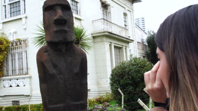 Young-Woman-photographer-taking-pictures-of-Moai-statue-at-Vina-del-Mar,-Chile
