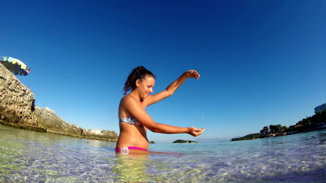 Beautiful-girl-play-with-sand-and-having-fun-in-sea-shallow-waters