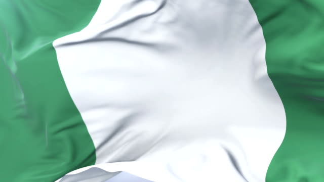 Bandera-de-Nigeria-ondeando-al-viento-en-lento-en-cielo-azul,-lazo