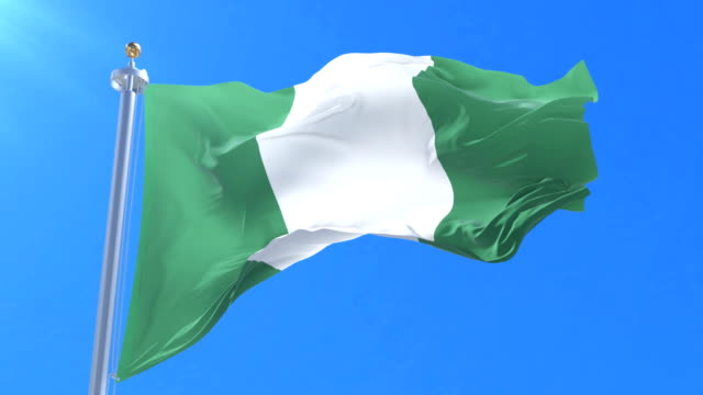 Nigeria-flag-waving-at-wind-in-slow-in-blue-sky,-loop