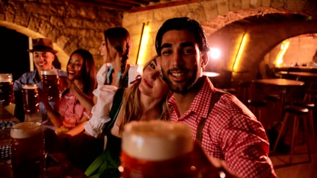 Young-multi-ethnic-friends-celebrating-Oktoberfest-with-beer-in-traditional-bar