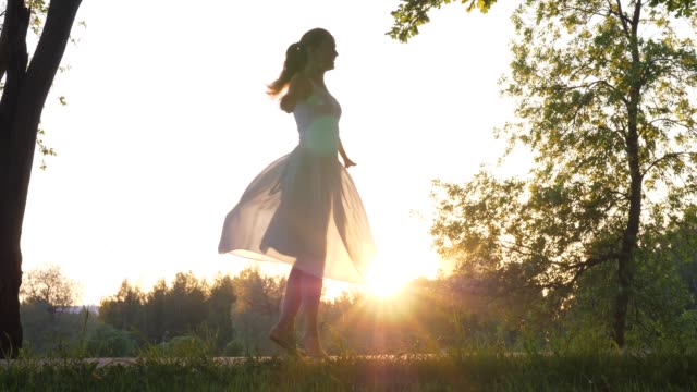 Young-woman-dancing-and-spinning-around-against-evening-sun