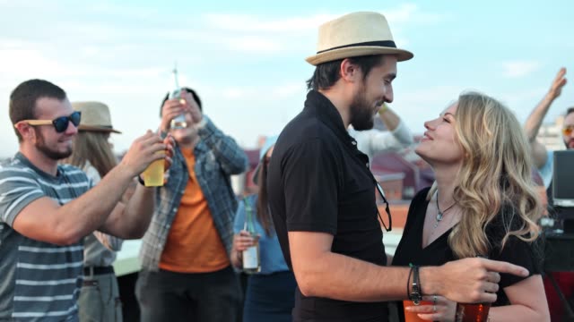 Schöne-junge-Paar-lachen-und-leidenschaftlich-küssen-am-Sommerfest-auf-dem-Dach