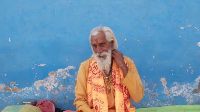 Hindu-Sadhu,-Heiliger-Mann,-sitzen-und-im-Gespräch-mit-Menschen-hinter-der-Kamera-in-Pushkar,-Rajasthan