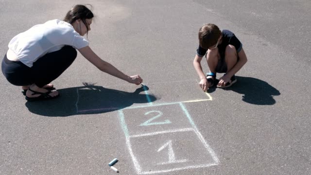 Mother-and-son-drawing-together-hopscotch-on-the-pavement.