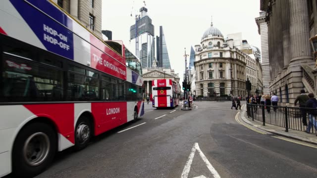 Autobuses-de-dos-pisos-de-bandera-británica-pasando-durante-hora-de-acometidas-de-la-mañana-en-el-distrito-financiero-de-Londres,-Reino-Unido.