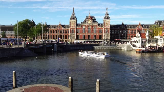 Tourist-boat-on-the-canal-in-front-of-Amsterdam-Central-station,-Europe.