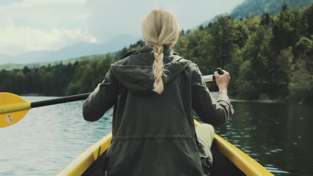 Girl-traveler-swims-in-boat-on-mountain-lake.