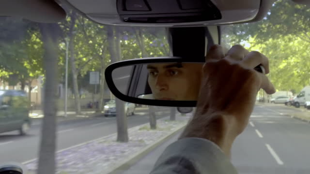 Serious-male-driver-adjusting-car-mirror-during-ride