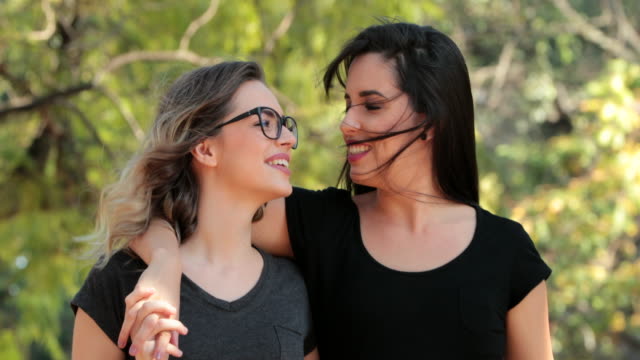 Zwei-Freundinnen-zusammen-zu-Fuß-in-den-Park,-umarmen-und-küssen-einander.-LGBT-paar-zu-küssen.