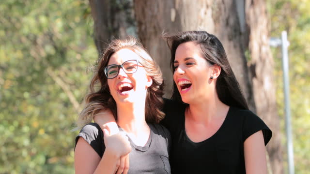 Zwei-Freundinnen-zusammen-zu-Fuß-in-den-Park,-umarmen-einander-lachen