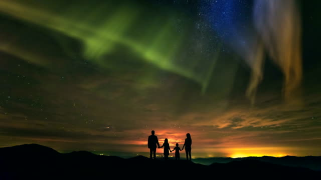 The-family-standing-on-the-mountain-on-the-northern-light-background.-time-lapse
