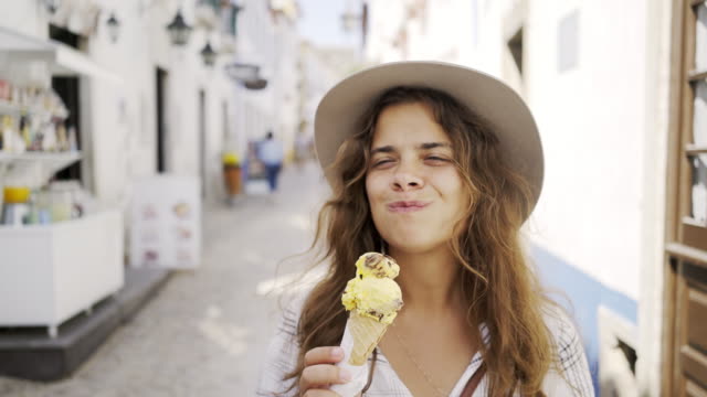 Smiling-woman-eating-ice-cream-on-town-street