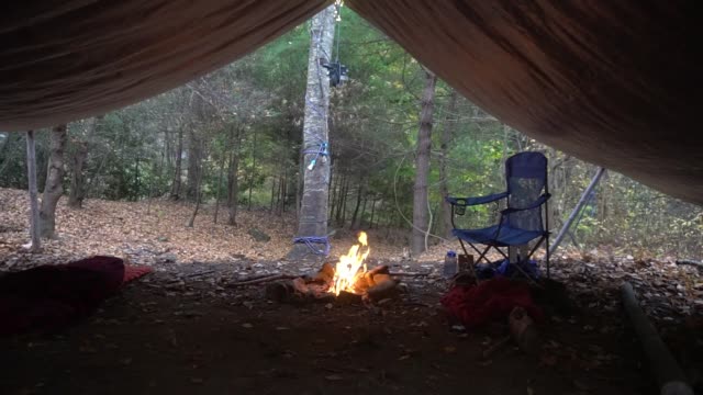 Kettle-and-pot-hanger-with-campfire-and-fairy-lights.-Survival-Bushcraft-setup-in-the-Blue-Ridge-Mountains-near-Asheville.-Primitive-Tarp-Shelter