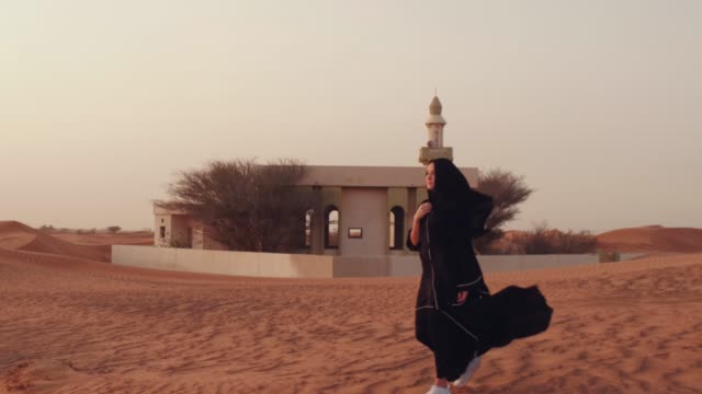 Mujer-musulmana-de-pie-cerca-de-la-mezquita-en-el-desierto.-Viento-fuerte-Paz-de-Oriente-Medio-sin-guerra