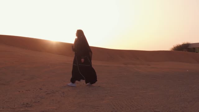 Muslimische-Frau-steht-in-der-Nähe-von-Moschee-in-der-Wüste.-Starker-Wind-Nahostfrieden-ohne-Krieg