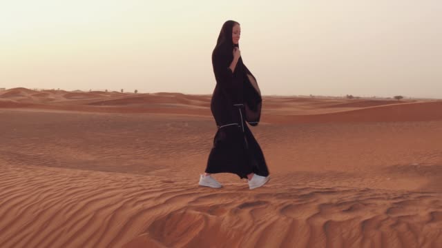 Muslim-woman-standing-near-mosque-in-the-desert.-Strong-wind-Middle-East-peace-without-war