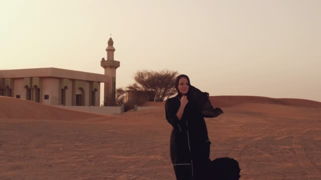 Mujer-musulmana-de-pie-cerca-de-la-mezquita-en-el-desierto.-Viento-fuerte-Paz-de-Oriente-Medio-sin-guerra