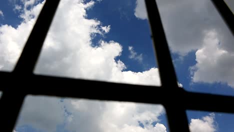 Barras-de-celda-de-prisión-y-cielo-azul,-pan-shot