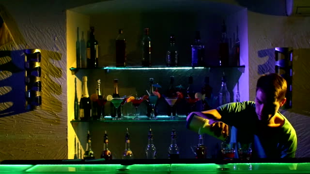 Professional-barman-making-cool,-amazing-tricks-using-bottle,-juggling-standing-behind-the-bar,-catching,-throwing-up,-and-pouring-two-liquids,-slow-motion