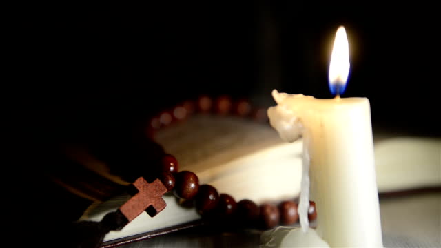 Kerzen-brennen-auf-dem-Hintergrund-der-heilige-Buch-und-einem-cross