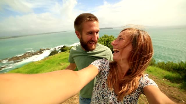 Junges-Paar-übernehmen-grasbewachsenen-Küste-Hügel-eine-Selfie-Porträt.